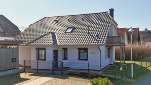 Ein eingeschossiges Haus mit einem Ziegeldach, einer Veranda und einem kleinen Garten.