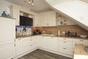 A modern kitchen with white cabinetry, a wooden countertop, a black microwave, and a coffee maker. - House Clemens in the Baltic seaside resort of Thiessow (Thiessow)