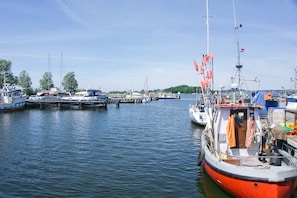 A marina with various boats docked, including a prominent red boat in the foreground. - House Clemens in the Baltic seaside resort of Thiessow (Thiessow)