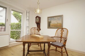 A dining room with a wooden table, two chairs, a chandelier, a clock, and a framed painting. - Surfer's Paradise Wiek - Holiday apartment Luv (Wiek)