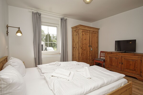 A bedroom with two beds, a wooden wardrobe, a television, and a window with curtains. - Wiek: A Surfer's Paradise - Luv Vacation Apartment (Wiek)