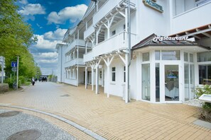 A white building with a restaurant sign, a covered walkway, and a clear sky. - Vacation apartment in a central and quiet location - Ferienwohnung Jasmund (Ostseebad Göhren)