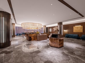 A modern lobby with a central bar, seating areas, and a decorative sculpture. - Crystal Hotel Qingdao May Fourth Square (Qingdao)