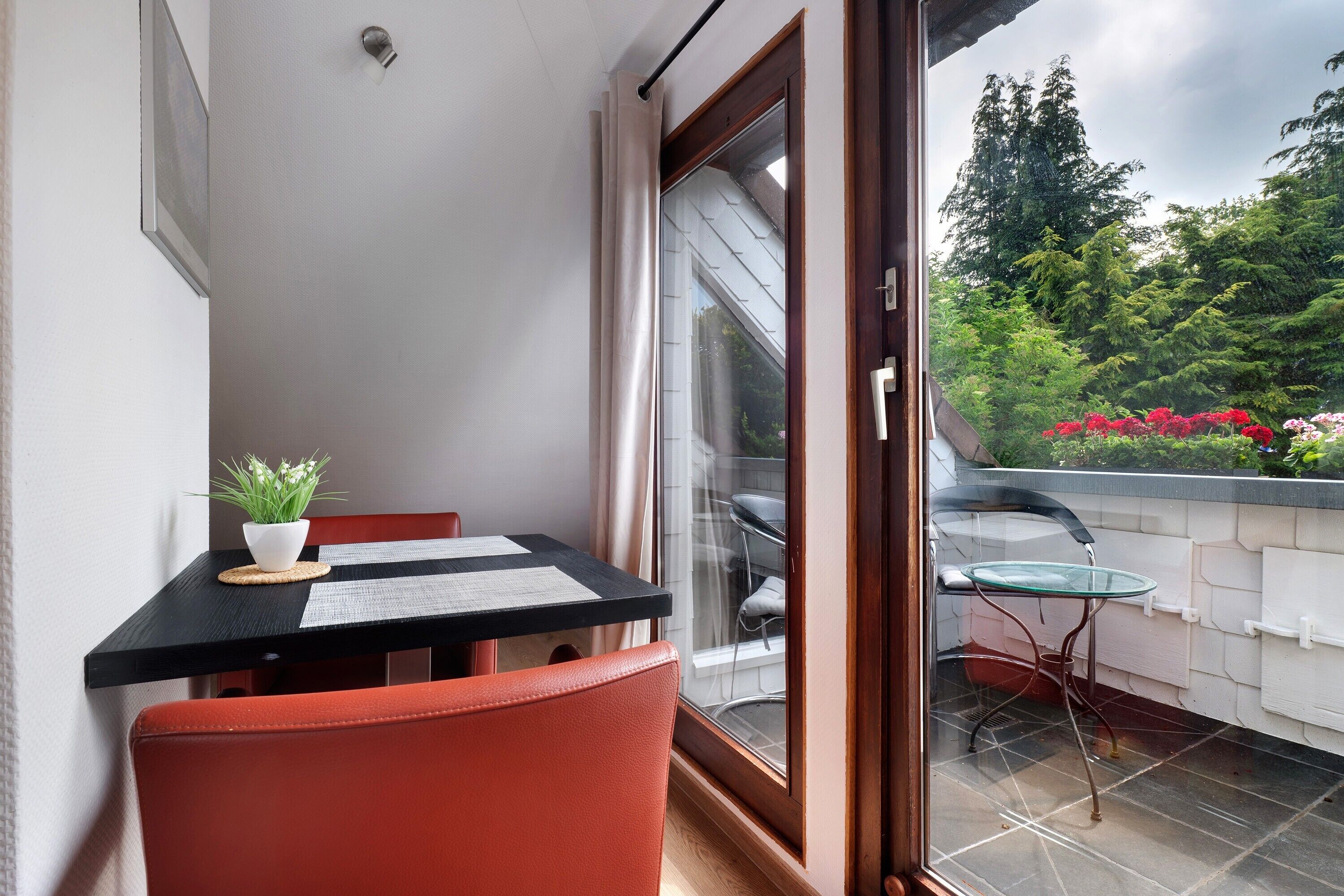 Ein Balkon mit Tisch, Stühlen und einem Blumentopf.