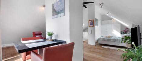 A modern interior with a dining area, a bed, and a kitchen in the background.