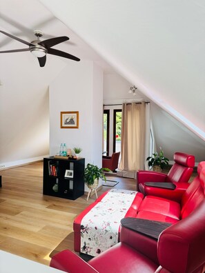 En moderne stue med en rød sofa, et sort multimøbel og en loftsvifte.