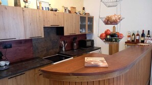 Una cocina moderna con armarios de madera, microondas integrado y una vinoteca con botellas.