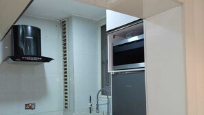 Una cocina equipada con estufa a gas, horno, refrigerador de acero inoxidable y extractor de aire negro.
