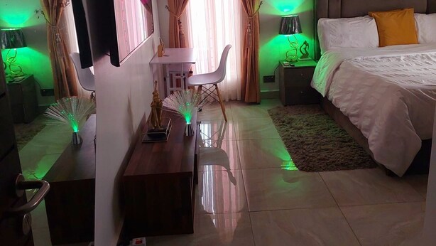 Un dormitorio moderno con una cama, un escritorio, una silla y un televisor.