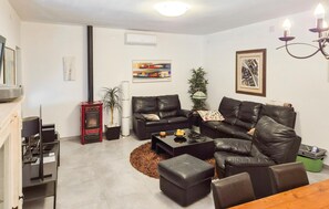 Ein modernes Wohnzimmer mit Kamin, Ledersofas, einem Couchtisch und einem Essbereich.