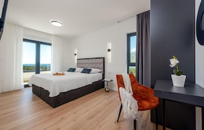 A modern bedroom with a large bed, a desk, a chair, and a potted plant. - Gorgeous home in Rovanjska (Rovanjska)