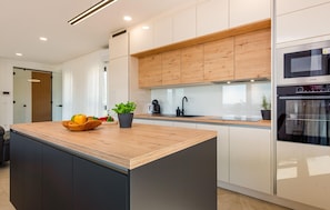 A modern kitchen with a wooden island, white cabinets, and stainless steel appliances. - Gorgeous home in Rovanjska (Rovanjska)