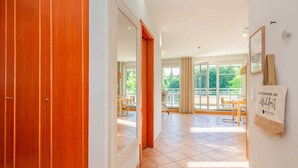 Corridoio di un hotel con porte in legno, pavimento piastrellato e vista su un'area pranzo all'aperto.