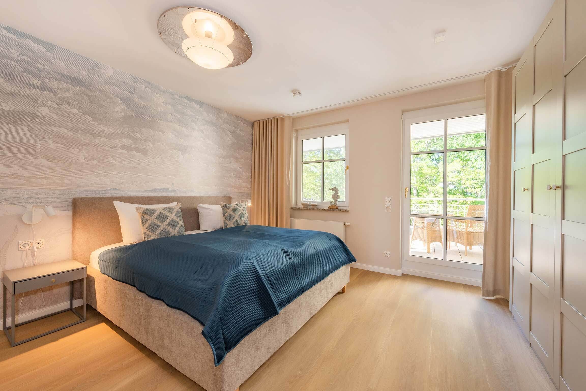 A bedroom with a bed, bedside table, window, and wardrobe.
