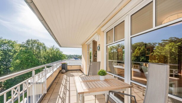 Un balcone con tavolo, sedie e una pianta in vaso.