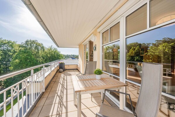 Ein Balkon mit Tisch, Stühlen und einem Blumentopf.