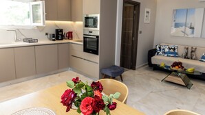 Une cuisine moderne dotée d’appareils électroménagers intégrés, un coin repas avec une table et des chaises, et un espace de vie avec un canapé et une table basse.
