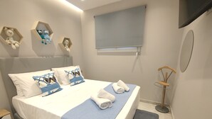 Un lit bien fait, avec une couverture bleue, des oreillers blancs et une tête de lit bleue.