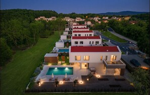 Una casa moderna con piscina, varias habitaciones y vistas a un área boscosa.