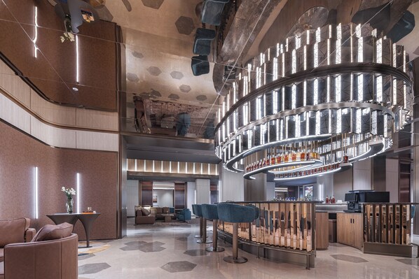 A modern hotel lobby with a curved bar, seating area, and a unique ceiling design. - Crystal Hotel qingdao wusi plaza haijing (Qingdao)