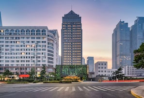 A cityscape with modern high-rise buildings, a central building with a prominent feature, and a crosswalk in the foreground.