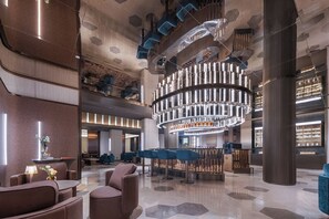 Um lobby moderno com assentos, área de bar e um lustre exclusivo.