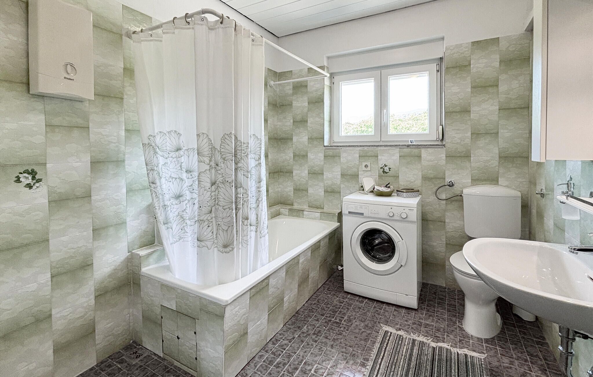 Een badkamer met een douche, een wasmachine, een toilet en een wastafel.