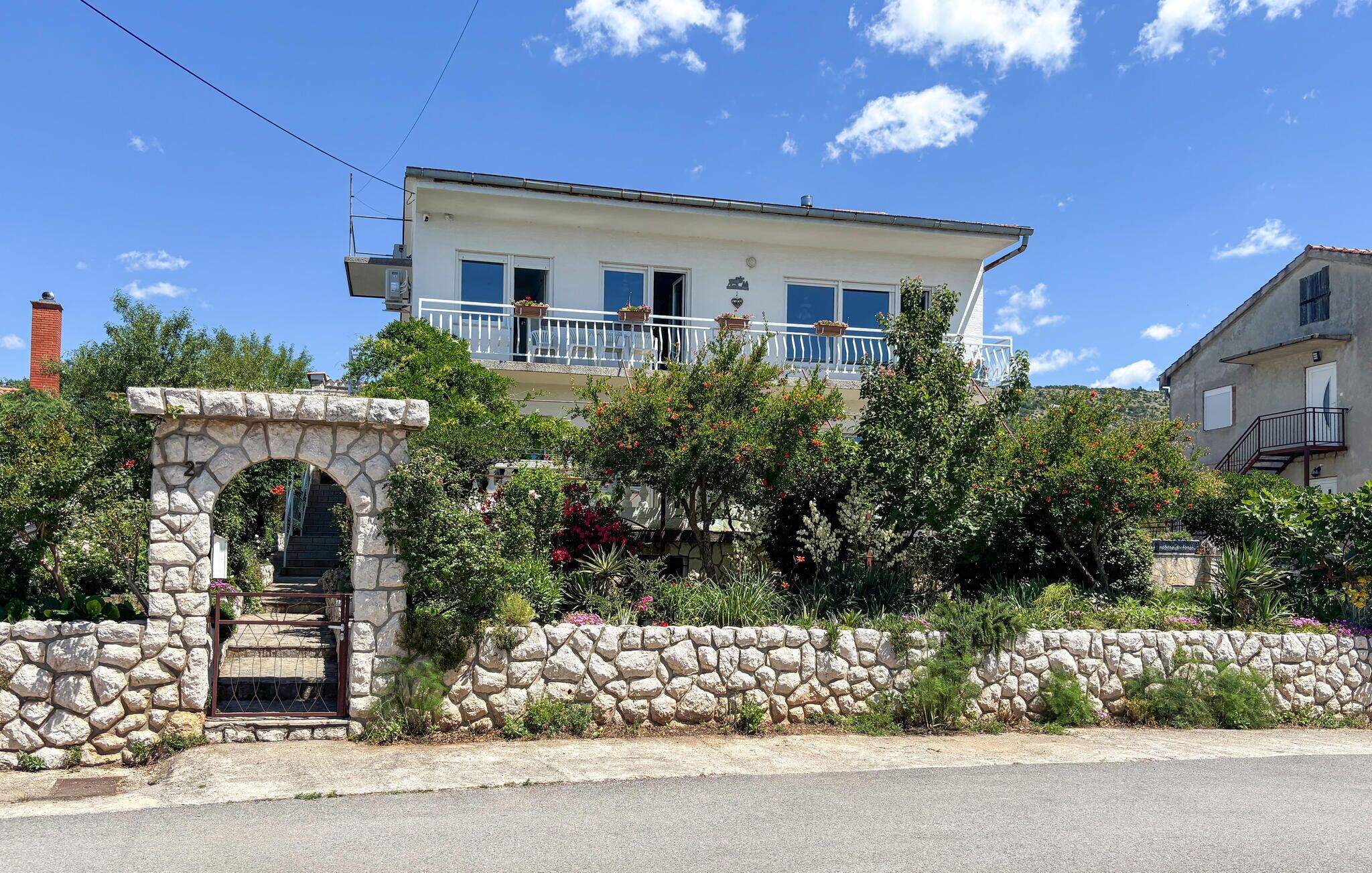 Un bâtiment à deux étages doté d’un balcon, d’une arche en pierre et d’un mur en pierre.