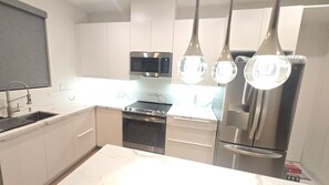 Une cuisine moderne avec des meubles blancs, une cuisinière en acier inoxydable, un four à micro-ondes et un réfrigérateur.