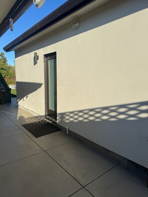 Ein Gebäude mit einer Tür, einem kleinen Fenster und einem Lüftungsgitter an der Wand.