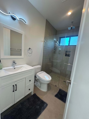 A modern bathroom with a glass-enclosed shower, a white sink, and a toilet.