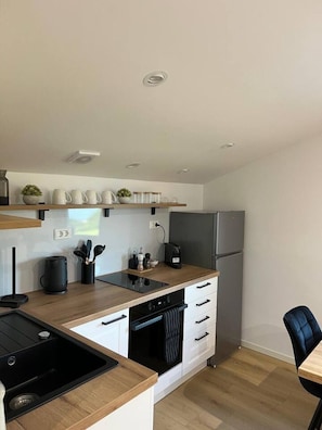 Eine moderne Küche mit Backofen, Kaffeemaschine und Kühlschrank.
