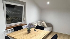 Een eetruimte met een houten tafel, zwarte stoelen, een potplant en een bank.