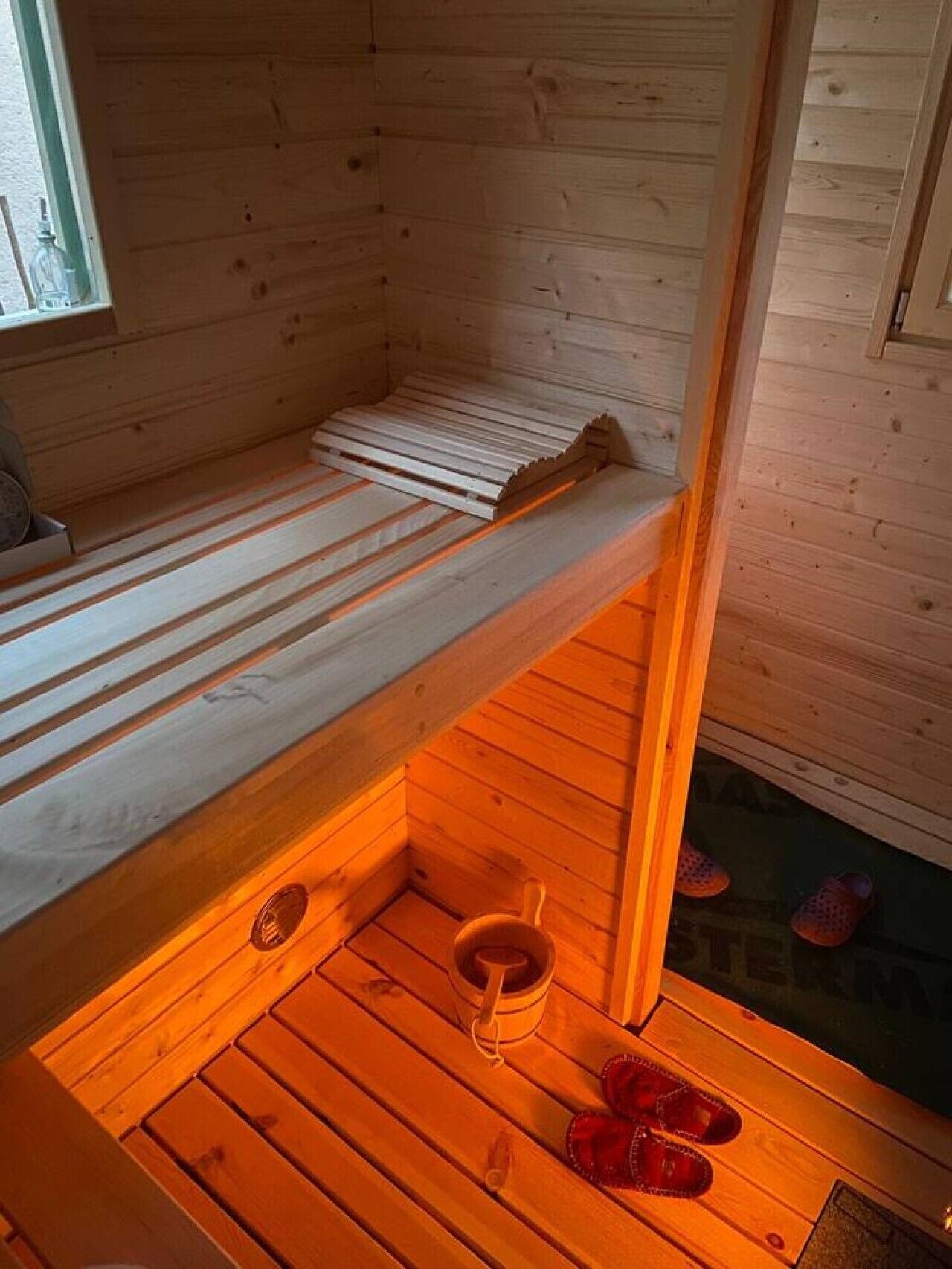 Eine Holzhütte mit einem Stockbett, einem kleinen Holztisch und einem Paar Hausschuhen.