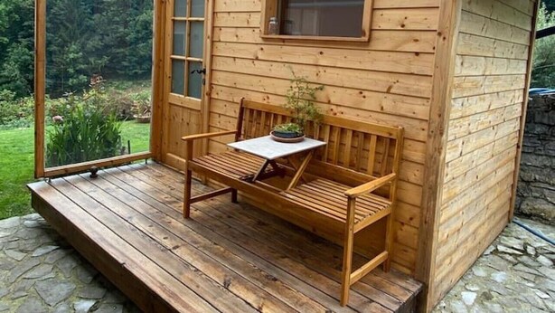Een houten chalet met een veranda, een bank, een tafel en een raam.
