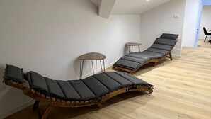 Een kamer met twee houten lounge fauteuils met kussens, een klein rond tafeltje en een houten vloer.