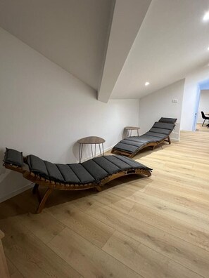 Ein Zimmer mit zwei Holz-Loungestühlen mit Kissen, einem kleinen runden Tisch und Holzboden.