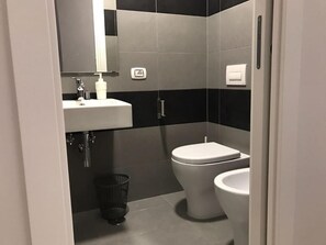 Et moderne badeværelse med en hvid vask, toilet og bidet.