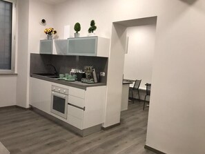 Et moderne køkken med hvide skabe, indbygget ovn og en bordplade med vask.