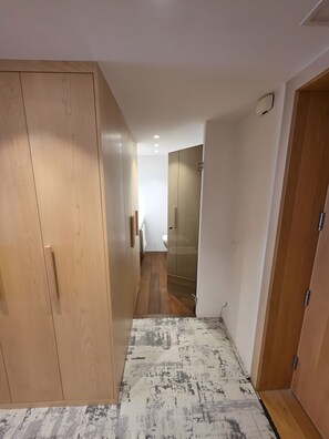 Un pasillo que conduce a un baño con un armario de madera y un tapete estampado.