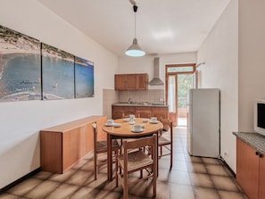 Une cuisine compacte avec des meubles en bois, une table à manger avec des chaises et un réfrigérateur.