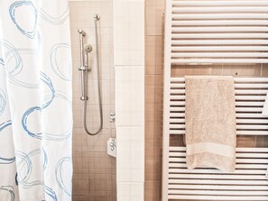 Een badkamer met een douche, handdoekrek en een douchegordijn met een patroon.