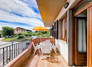 Un balcon avec une table et des chaises, un parasol et une vue sur le paysage environnant.