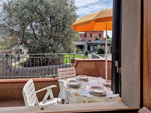 Un balcon avec une table dressée pour le repas, une chaise et un parasol orange.