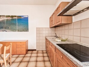 Une cuisine avec des meubles en bois, un plan de travail carrelé, un évier et une cuisinière.