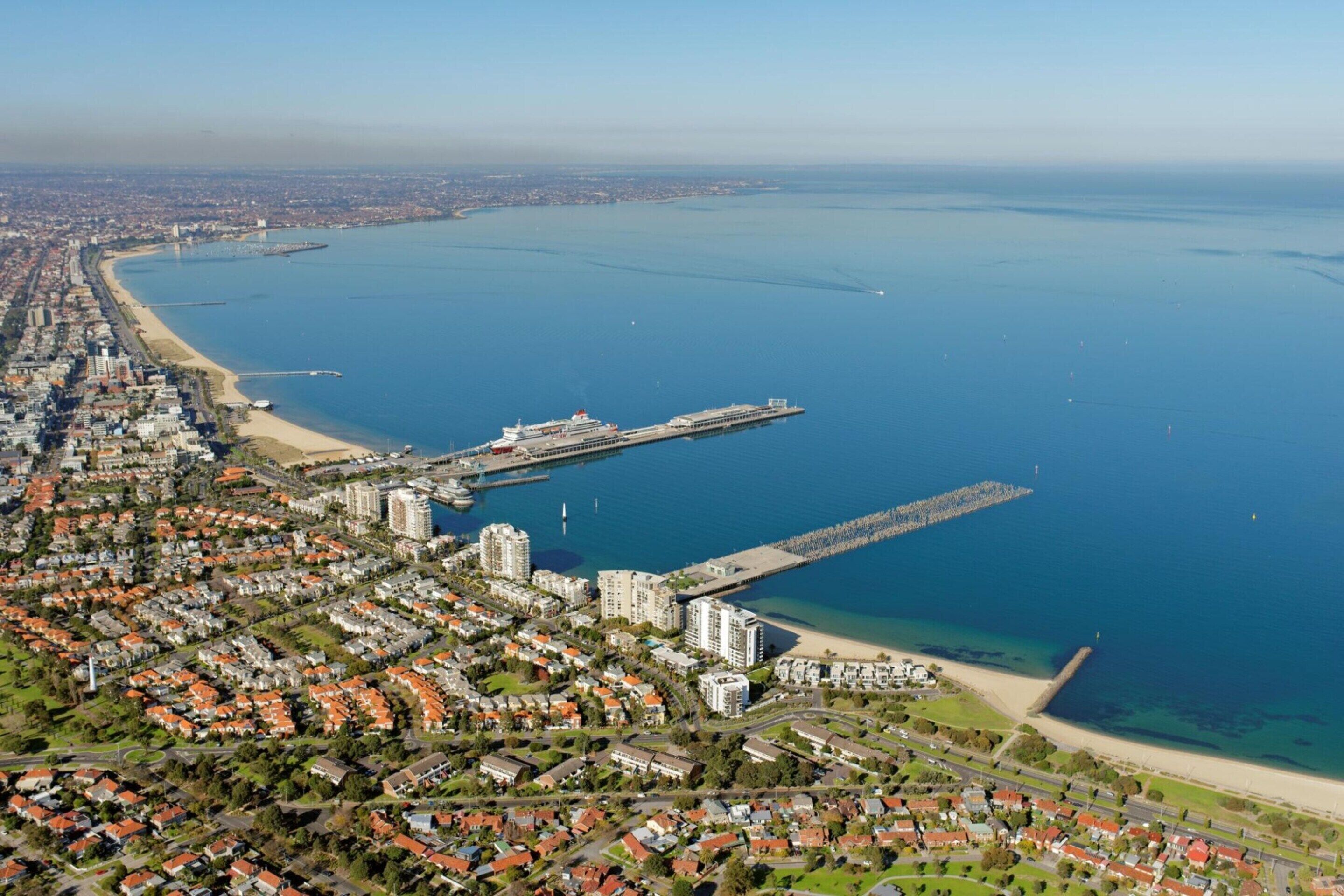 An aerial view of a coastal city with residential areas, a beach, and a large body of water.