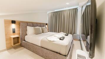 Un dormitorio moderno con una cama grande, cabecera de madera, mesita de noche, espejo y vistas al exterior.