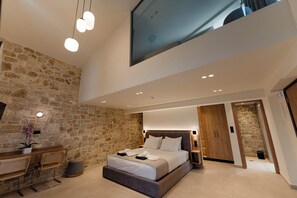 Um quarto moderno com parede de pedra, uma cama, uma escrivaninha e uma janela grande.
