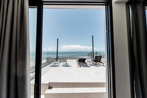 Een balkon met twee stoelen en een tafel, met uitzicht op een strand en de oceaan.