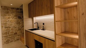 Una cocina moderna con armarios de madera, una pared de piedra y estantes empotrados.